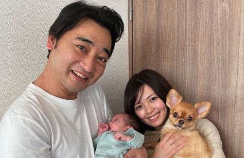 ジャンポケ斉藤さんが赤ちゃんを抱っこしている横に奥さんが犬を抱いている画像