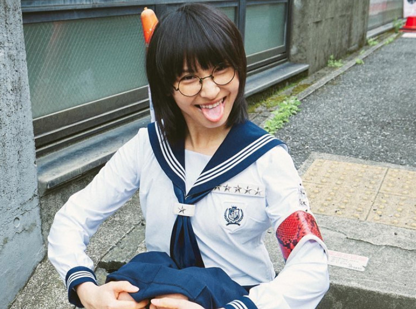 新しい学校のリーダーズSUZUKAが座って舌を出している画像
